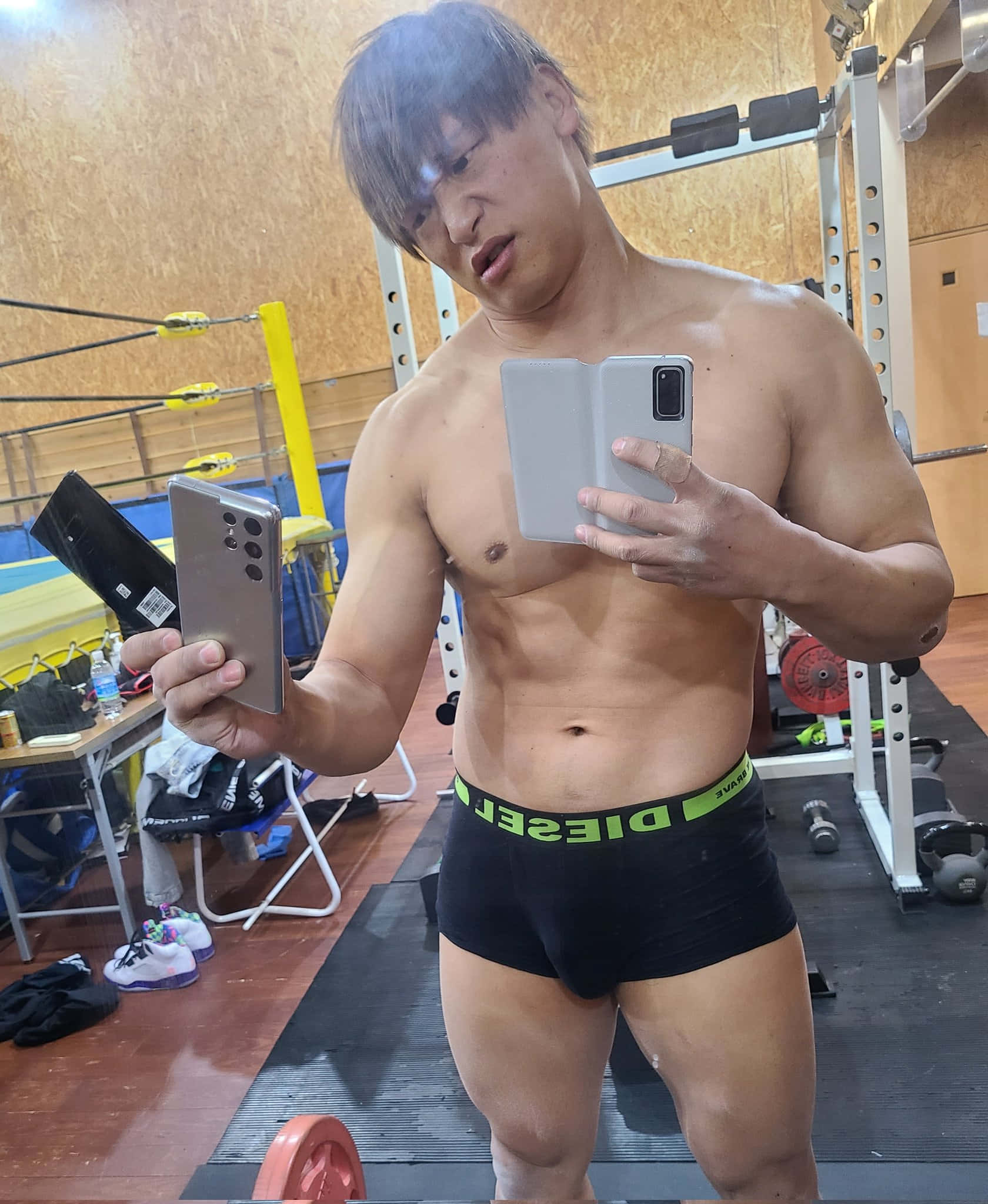 selfie 桌布 壁紙 — 一個肌肉發達的男人穿著黑色Diesel內褲，在健身房拿著兩支智慧型手機對著鏡子自拍。