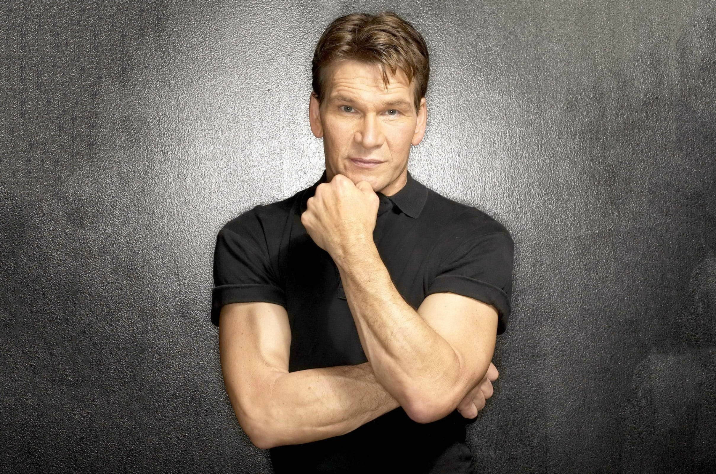actor 桌布 壁紙 — 一個肌肉發達的男人穿著黑色Polo衫，在紋理灰色背景前自信地擺姿勢，拳頭靠近下巴。