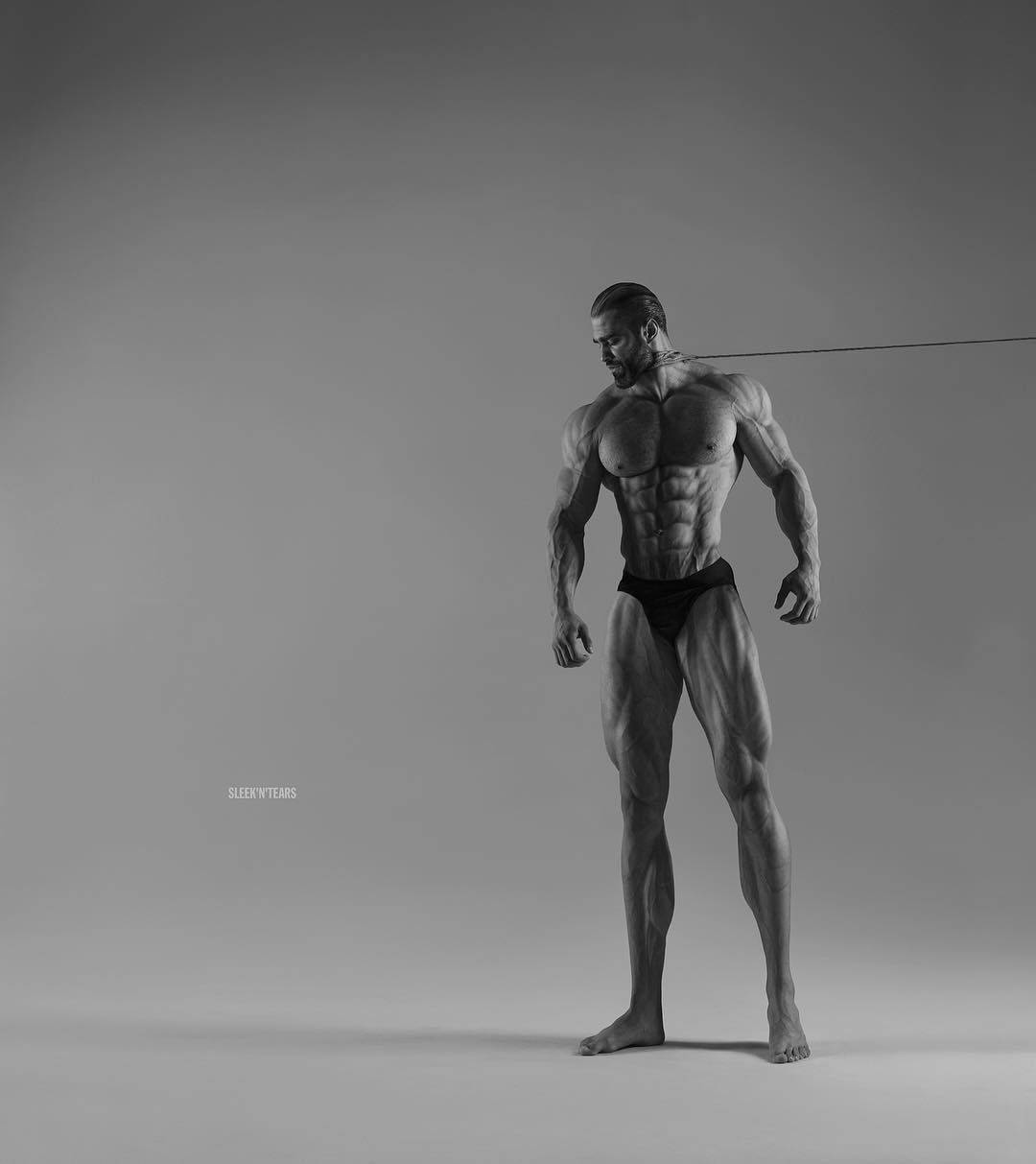 一個肌肉發達的男人在工作室中以清晰的體格和黑色內褲擺姿勢。