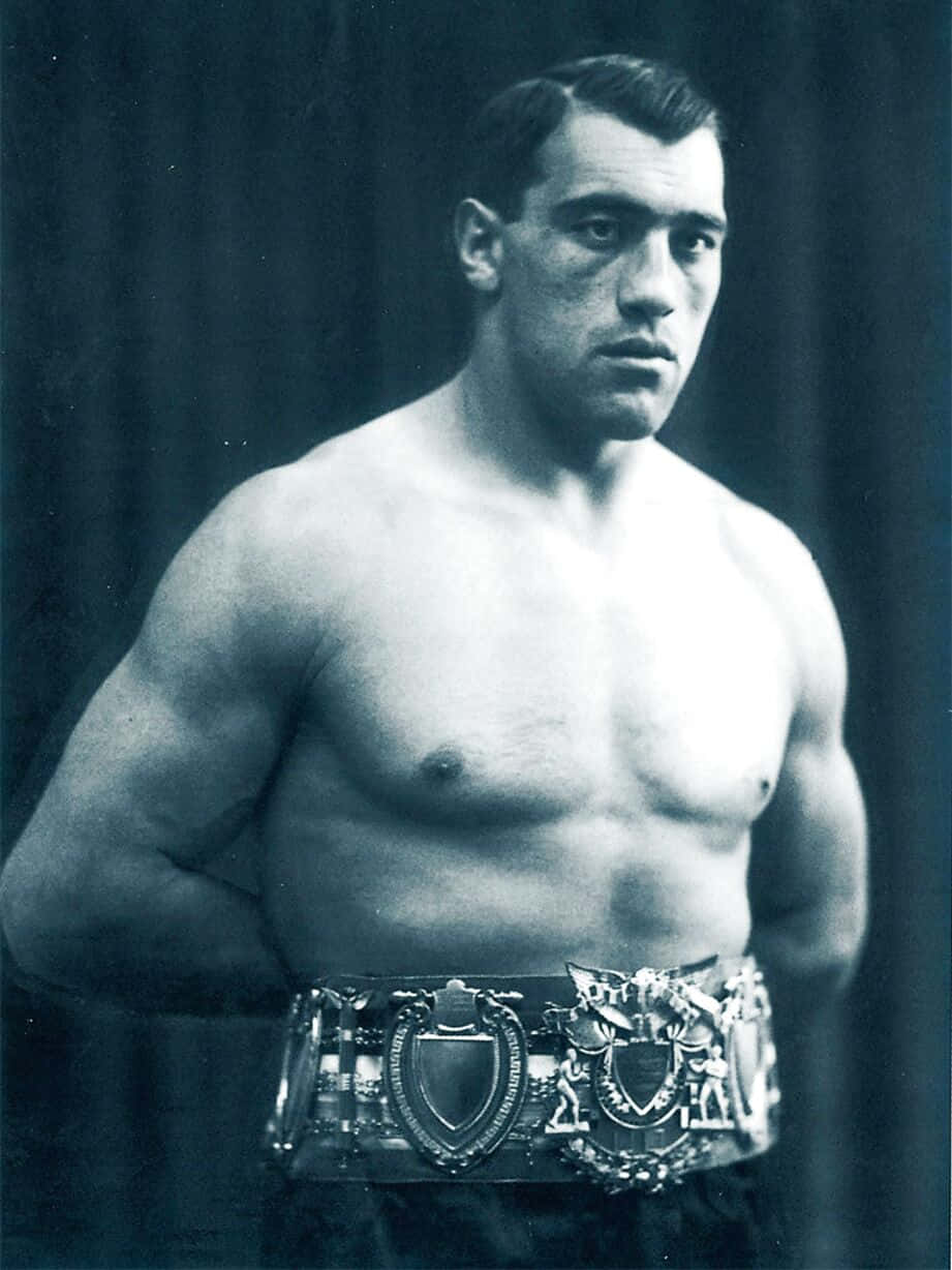Boxing 桌布 壁紙 — 一個肌肉發達的男人赤裸上身，戴著華麗的冠軍腰帶，站在深色窗簾背景前。