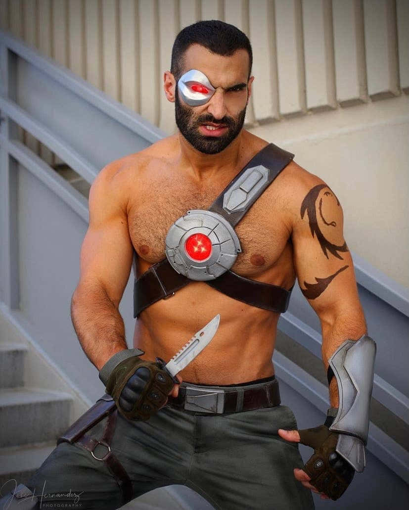 Mortal Kombat Cosplays 桌布 壁紙 — 一個肌肉發達的男子穿著細節豐富的《鬥陣特攻》死神角色扮演服裝，在混凝土樓梯上拿著刀擺姿勢。