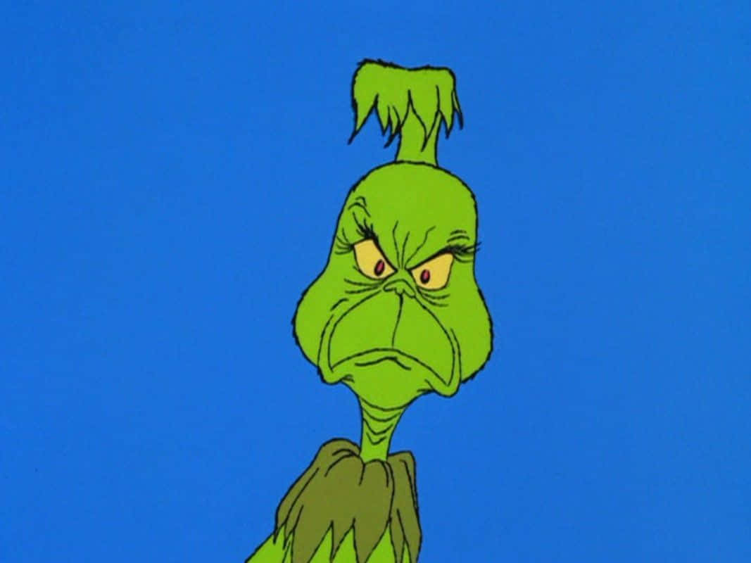 The Grinch 桌布 壁紙 — 一個脾氣暴躁的綠色卡通角色，有一撮頭髮和憤怒的眼睛，凝視著純藍色背景。