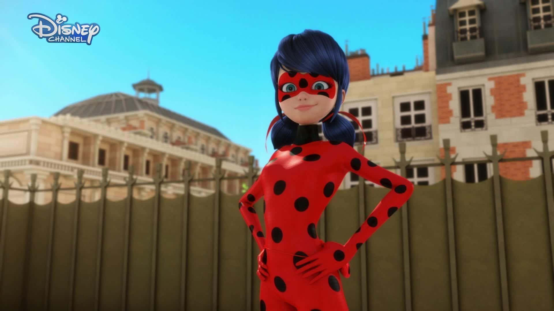 Miraculous 桌布 壁紙 — 一個自信的動畫女超級英雄穿著紅色圓點套裝，雙手叉腰，站在巴黎的圍欄和歷史建築前，背景是晴朗的藍天。