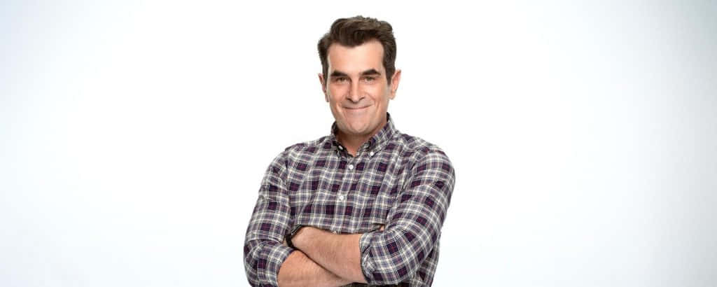 Ty Burrell 桌布 壁紙 — 一個自信的男人穿著格紋襯衫，雙手交叉站在純白色背景前。