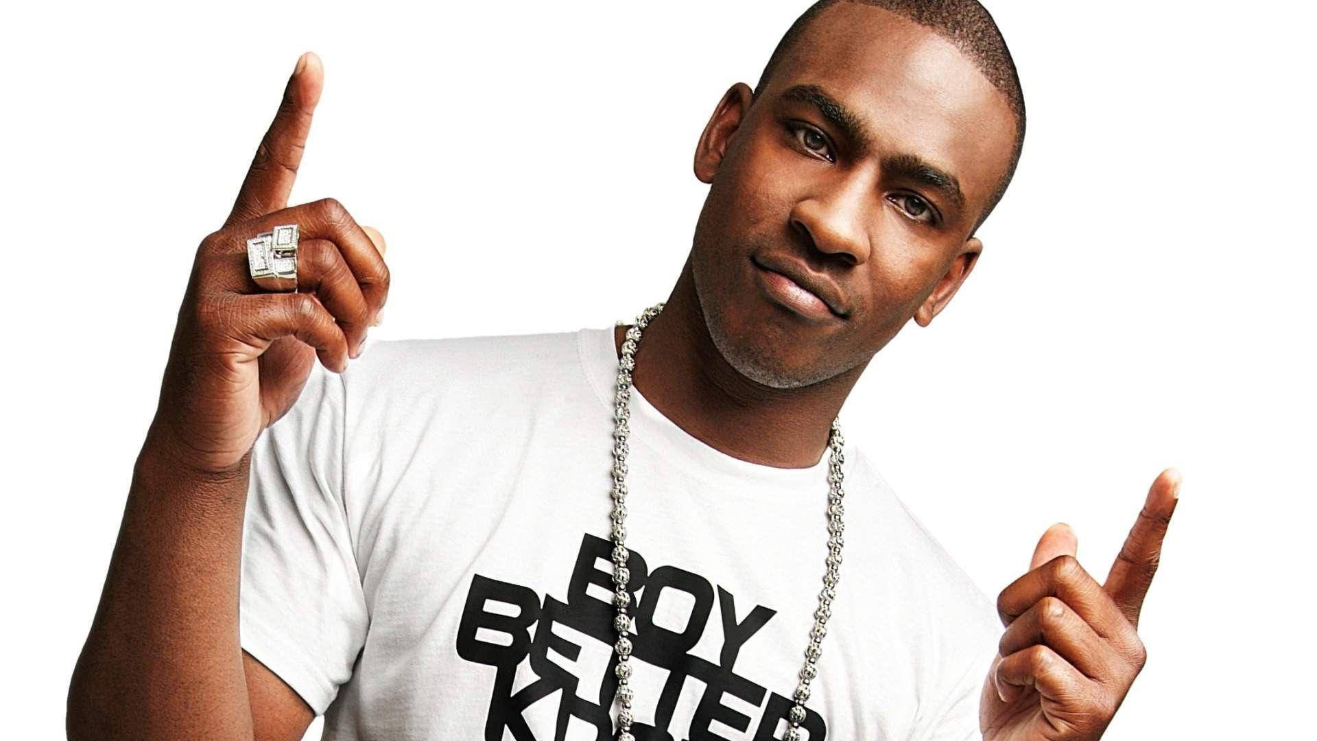 Skepta 桌布 壁紙 — 一個自信的男人穿著白色T恤，上面有粗體黑色文字，在純白背景上雙食指向上指。