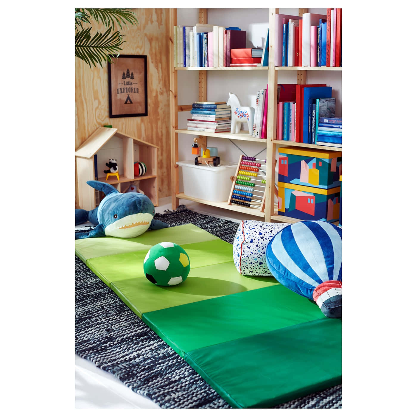 Gymnastics Mat 桌布 壁紙 — 一個舒適的兒童遊戲室，配有綠色地墊、毛絨玩具、色彩繽紛的書籍，以及裝滿遊戲和裝飾品的木架。