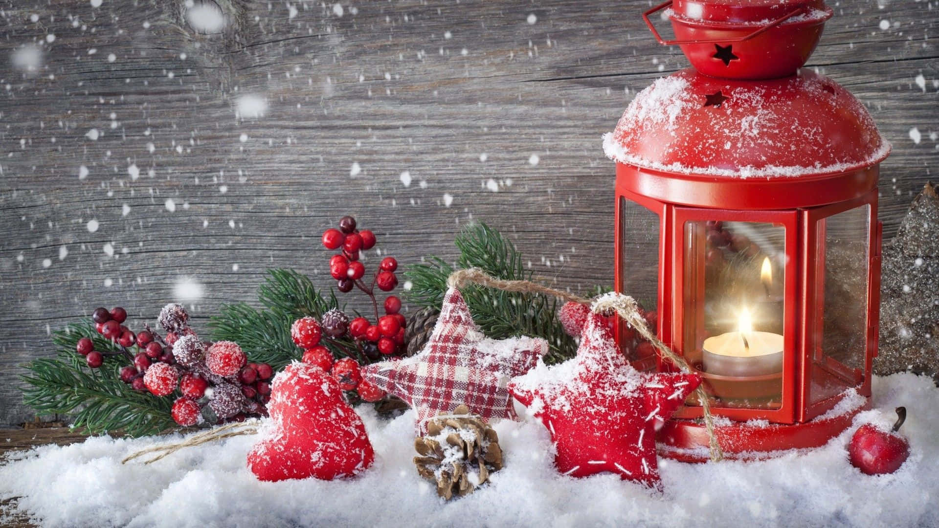 Snowy Christmas 桌布 壁紙 — 一個舒適的冬日場景，有發光的紅色燈籠、積雪的松樹枝和節日紅色裝飾品，放在雪白的木質表面上。
