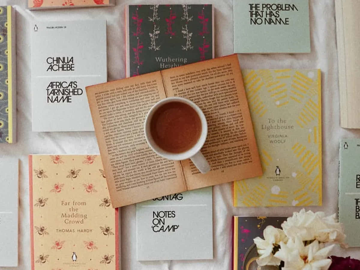 Aesthetic Books 桌布 壁紙 — 一個舒適的平鋪佈局，包括復古書籍和一杯冒煙的咖啡，放置在柔軟有紋理的表面上，並配有白色花朵。