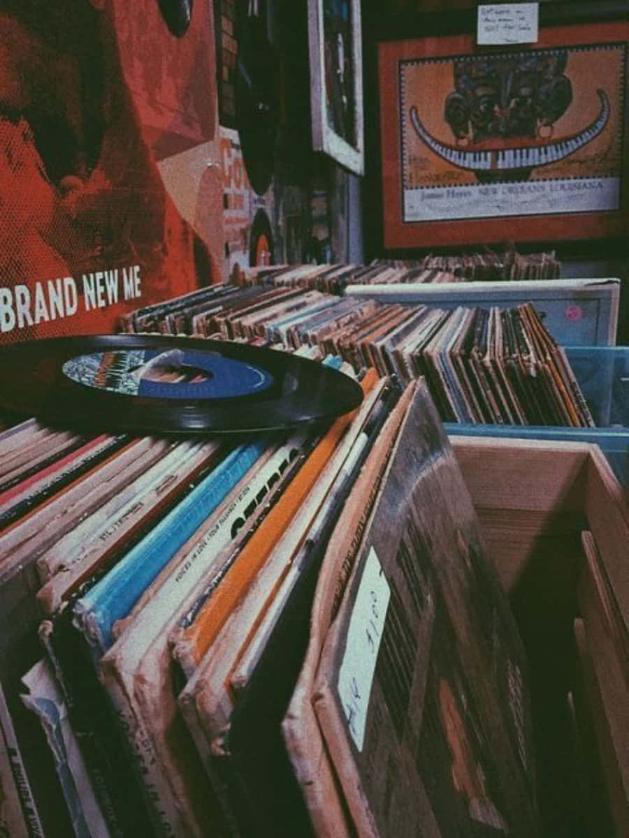 Vinyl Record 桌布 壁紙 — 一個舒適的復古唱片店角落，在溫暖的環境燈光下，堆滿了色彩繽紛的黑膠唱片和裱框的爵士海報。