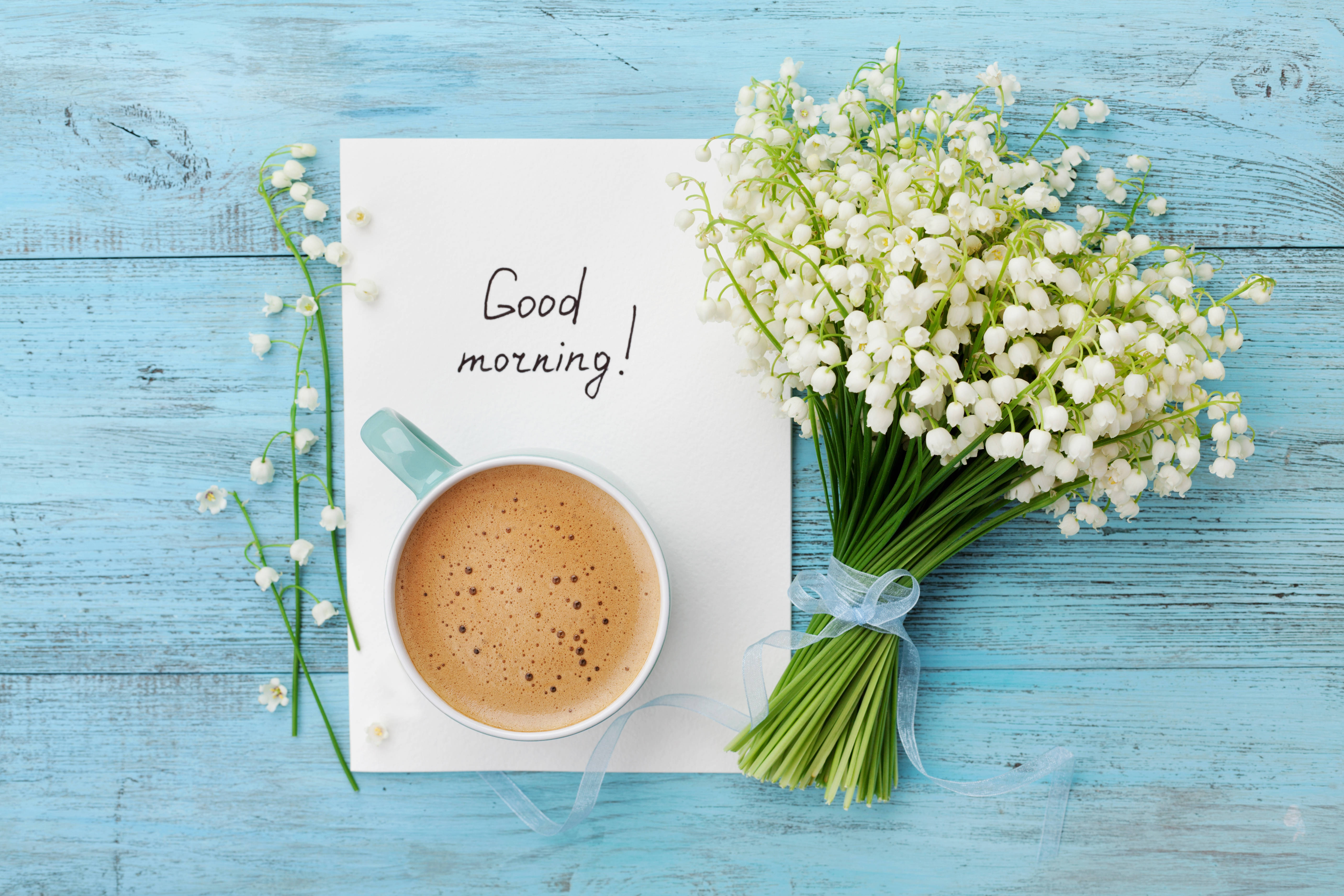 Morning 桌布 壁紙 — 一個舒適的早晨場景，一杯冒著熱氣的咖啡旁邊放著一張手寫便條和新鮮的白百合花束，在質樸的藍色木質表面上。