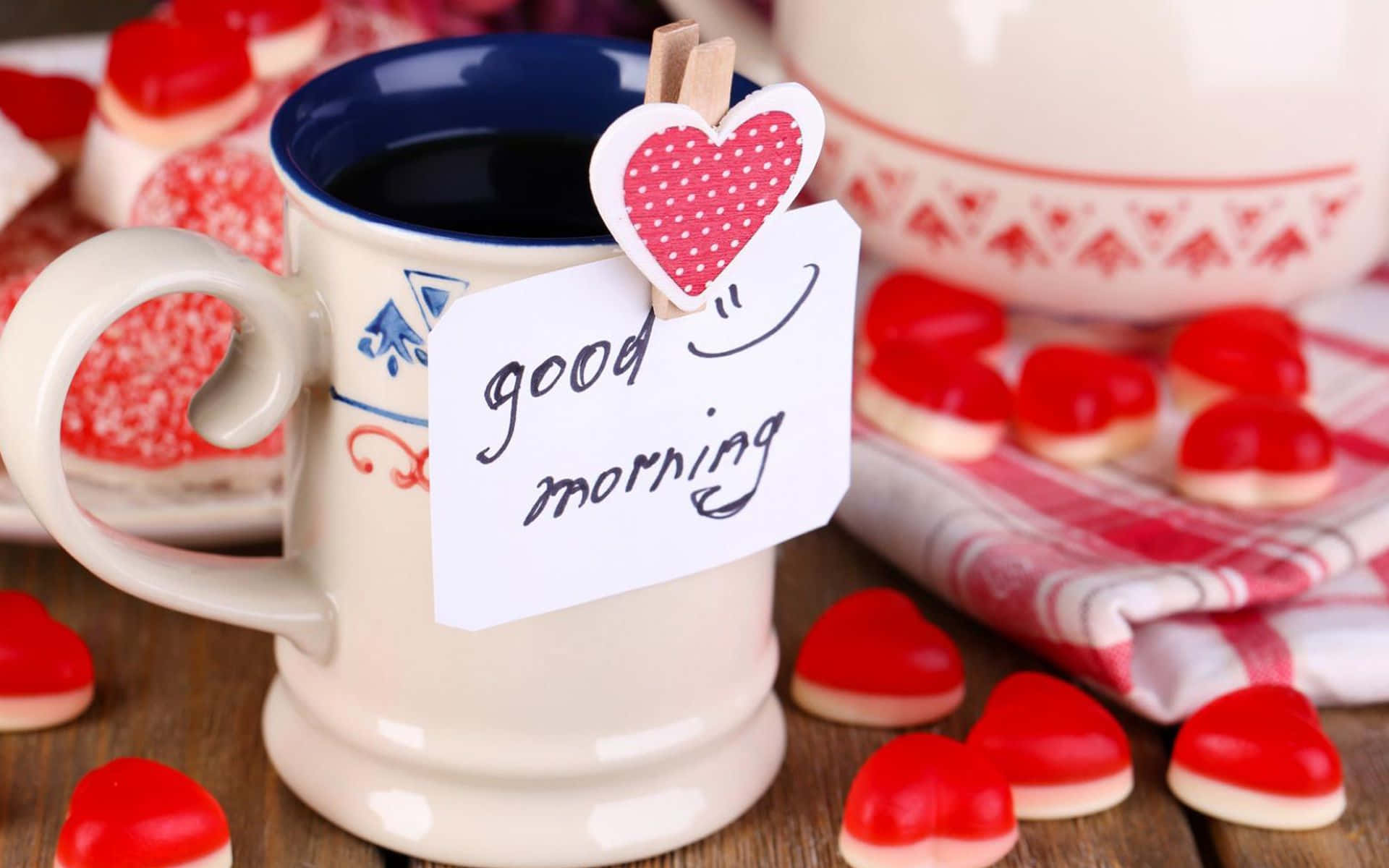 Good Morning 桌布 壁紙 — 一個舒適的早晨場景，陶瓷杯盛著黑咖啡，點綴著手寫便條和散落在木桌上的心形糖果。