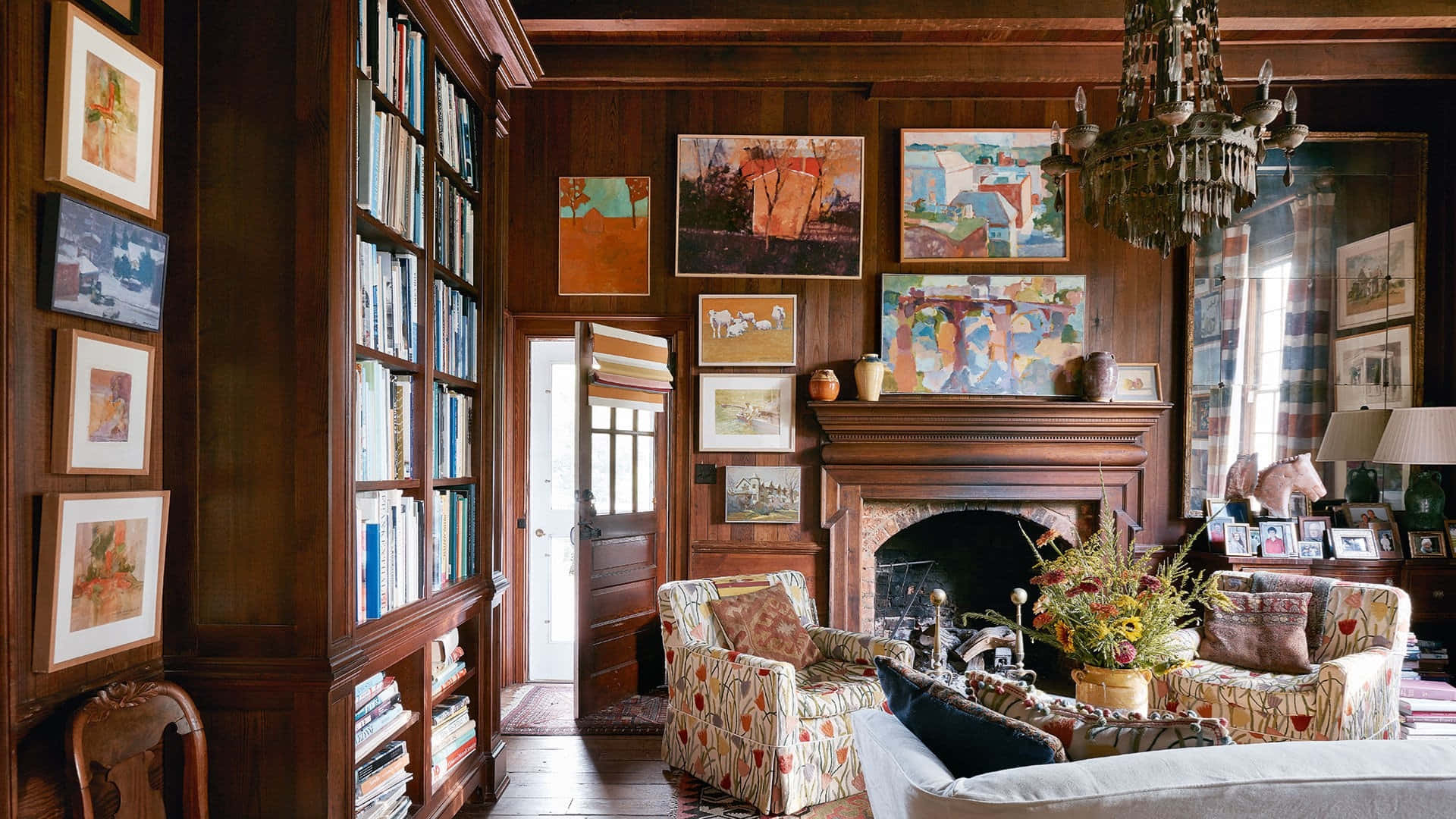 Interior Design 桌布 壁紙 — 一個舒適的木鑲板圖書館，配有書架、藝術品和壁爐，沐浴在溫暖的自然光中。