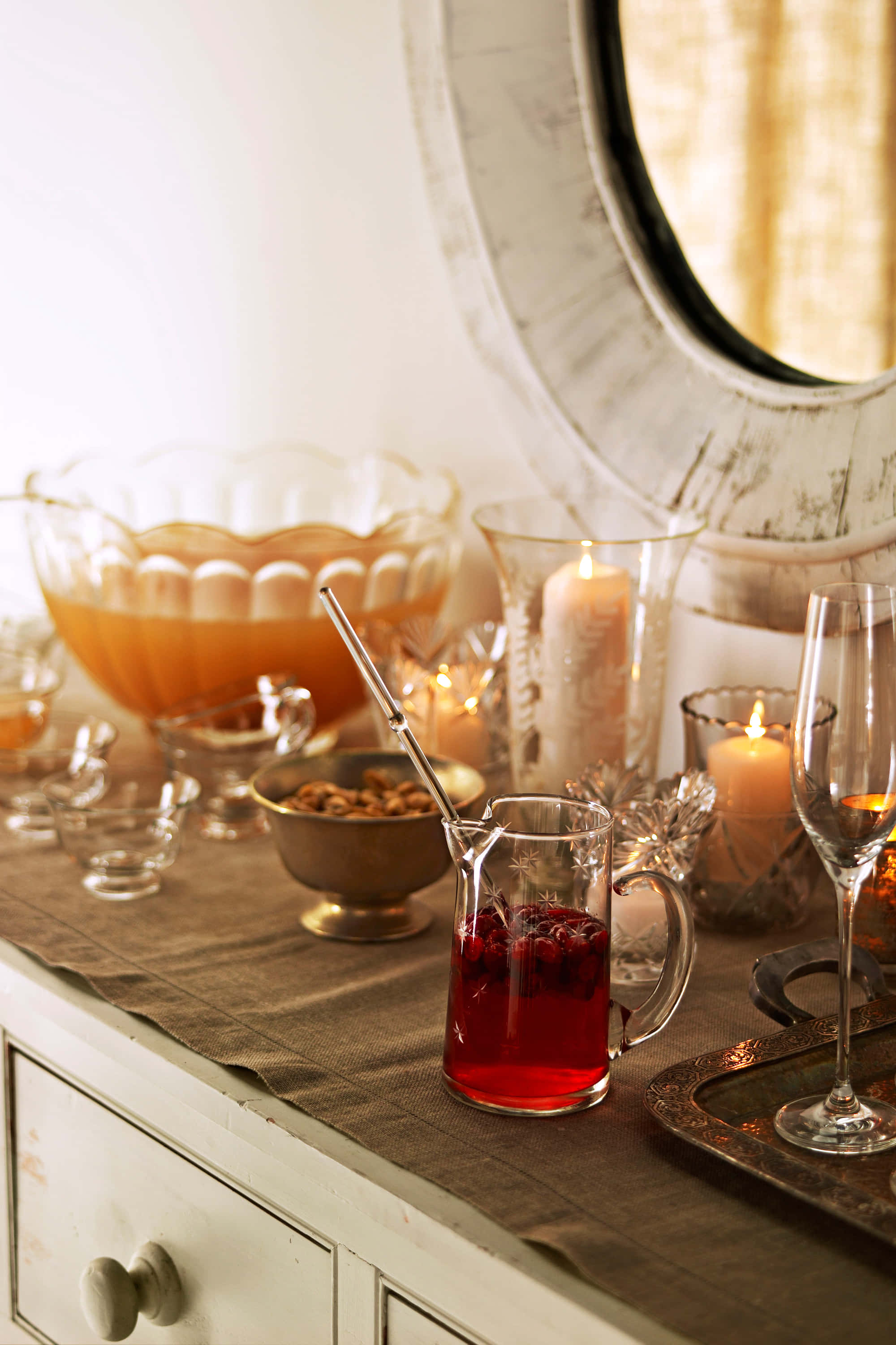 Winter Drinks 桌布 壁紙 — 一個舒適的桌面場景，有一壺紅色潘趣酒、蠟燭和一個沐浴在溫暖金色光芒中的大潘趣碗。