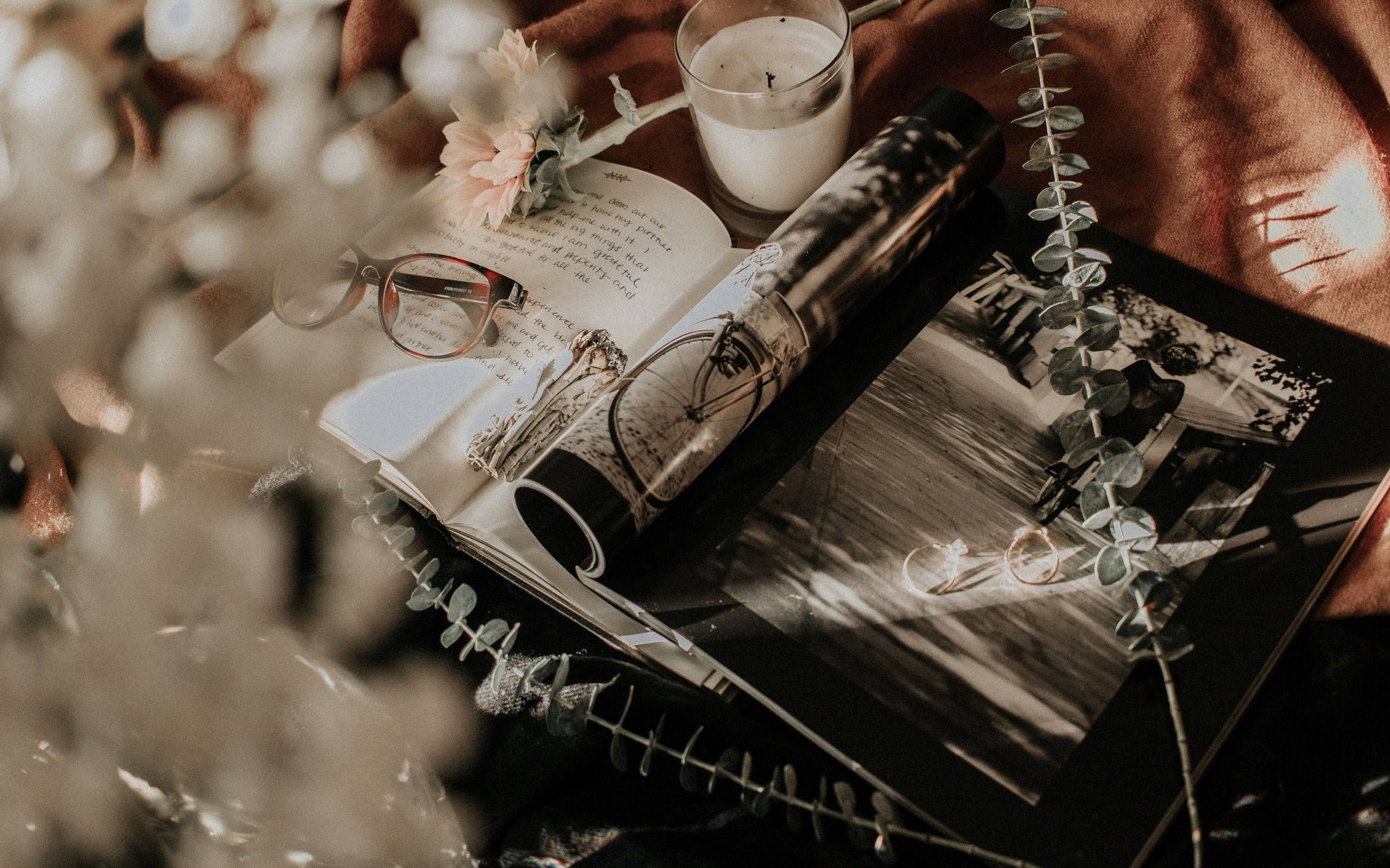 Wedding 桌布 壁紙 — 一個舒適的桌面場景，有一本打開的書、眼鏡、蠟燭和尤加利枝條，沐浴在溫暖的金色光線中。