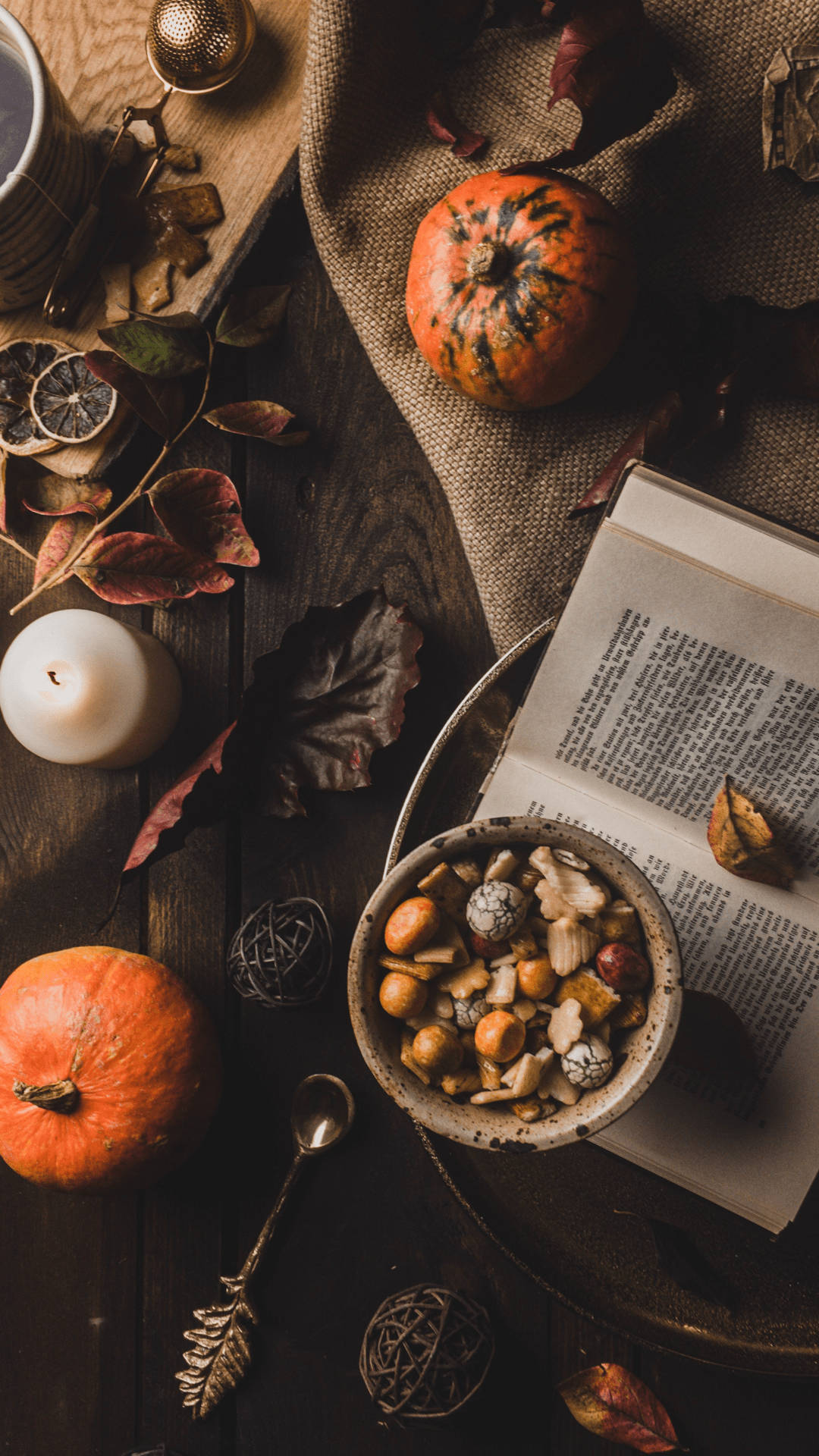 Autumn Season 桌布 壁紙 — 一個舒適的秋季靜物，有南瓜、堅果、樹葉和一本打開的書，放在質樸的木桌上。