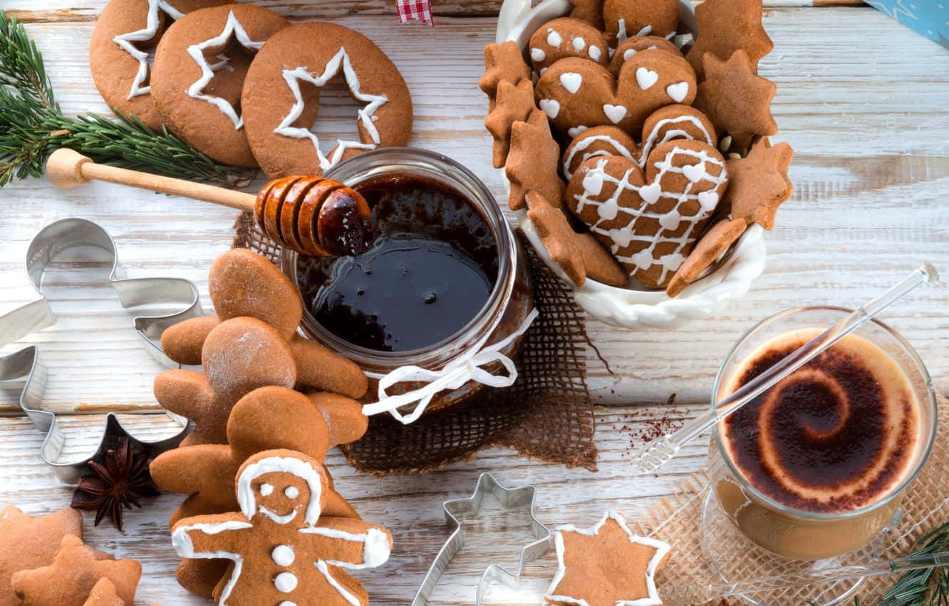 Winter Desserts 桌布 壁紙 — 一個舒適的節日擺盤，包含星星、心形和小人形狀的薑餅餅乾，配以蜂蜜蘸棒和咖啡，置於鄉村風木桌上。
