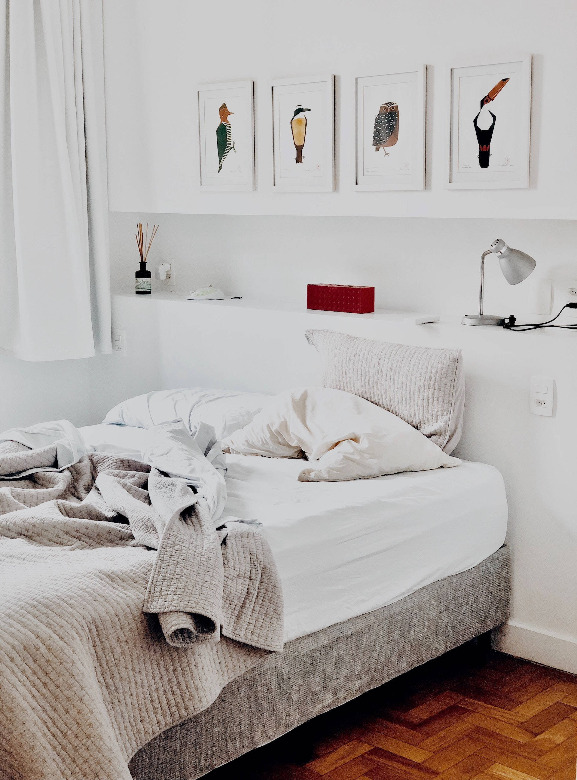 bed 桌布 壁紙 — 一個舒適的臥室，有一張凌亂的床、白色牆壁和木地板上的鳥類藝術品。