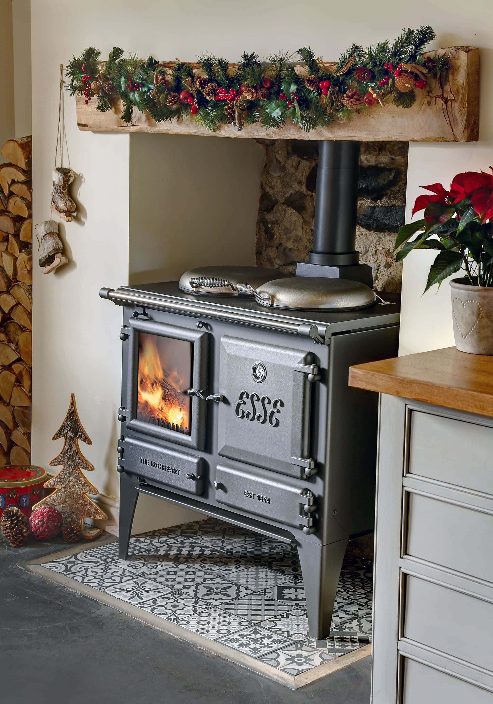 Stove 桌布 壁紙 — 一個舒適的鄉村風格壁爐，在復古爐灶中燃燒著熊熊烈火，並裝飾著節日花環和松果。