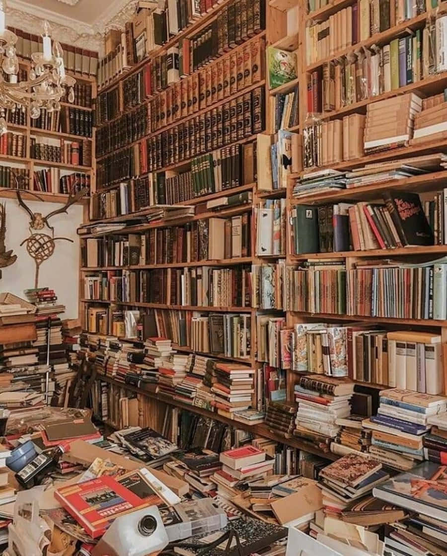 美學 桌布 壁紙 — 一個舒適雜亂的圖書館，充滿了高聳的木書架，上面堆滿了復古書籍，地板上散落著一堆堆的書。