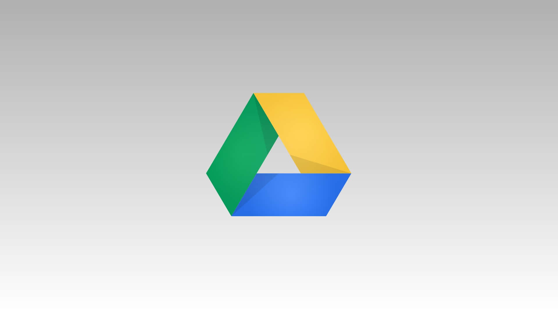 google 桌布 壁紙 — 一個色彩繽紛的Google Drive標誌，中央有綠色、黃色和藍色的三角形部分，置於柔和的灰色漸變背景上。
