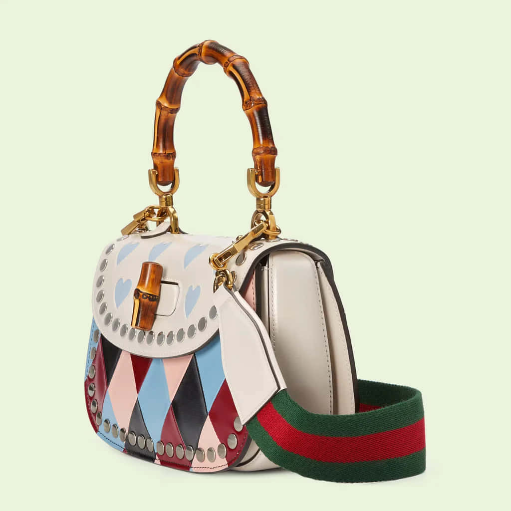 Gucci 桌布 壁紙 — 一個色彩繽紛的Gucci手提包，配有竹製手柄和心形圖案，放在淺綠色背景前。