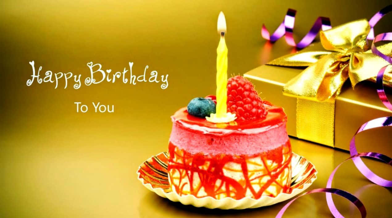 Zoom Birthday 桌布 壁紙 — 一個色彩繽紛的生日蛋糕，上面有一根點燃的蠟燭和新鮮莓果，旁邊是一個金色禮物盒，飾有紫色絲帶。