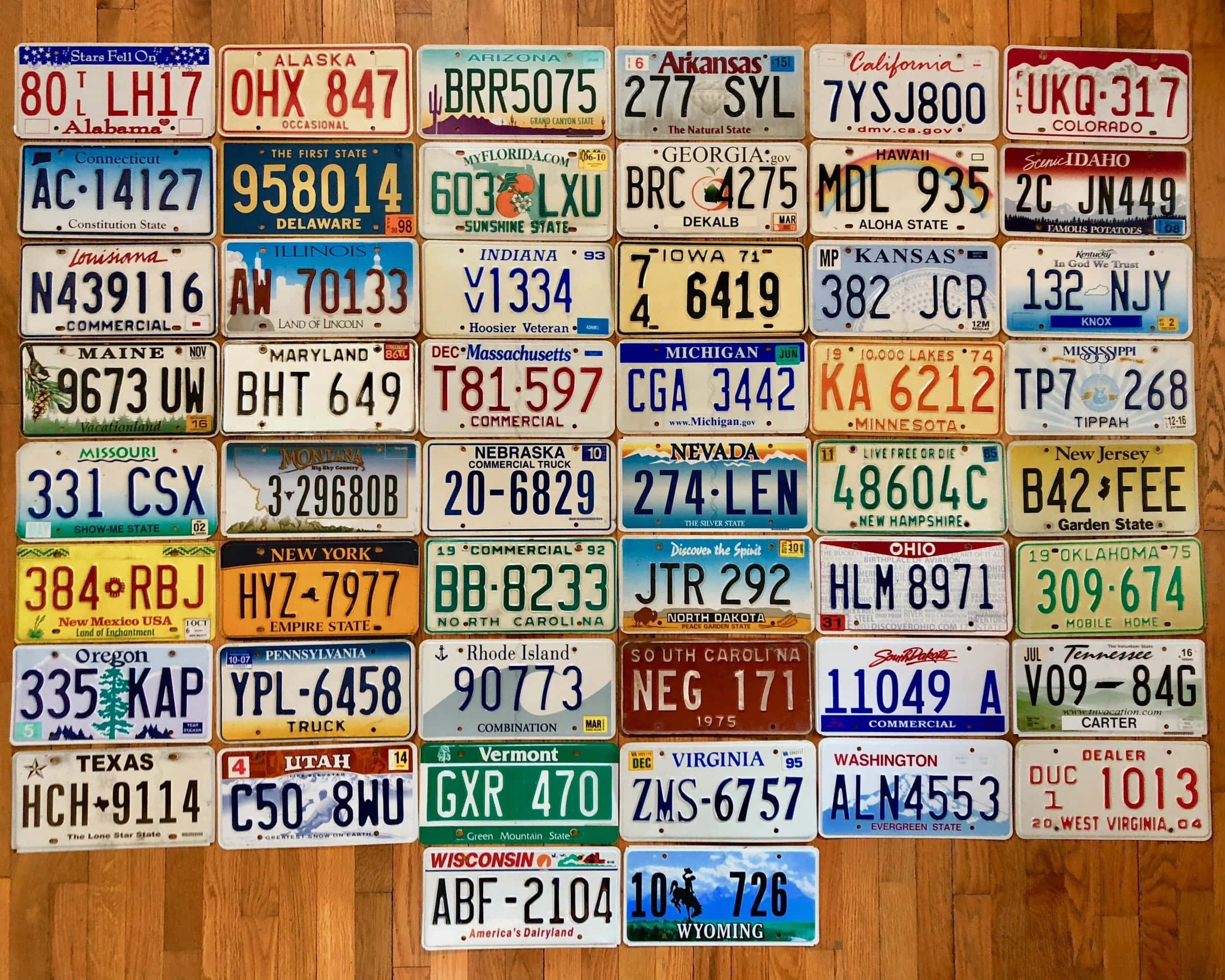 License Plate 桌布 壁紙 — 一個色彩繽紛的網格，整齊地排列在溫暖的木地板上，展示著復古的美國各州車牌。