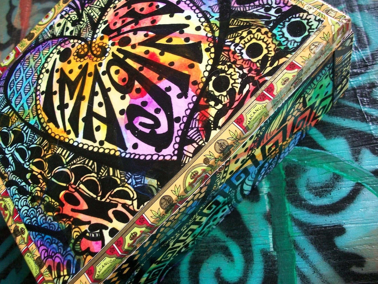 桌布 壁紙 — 一個色彩鮮豔的盒子，飾有複雜的迷幻圖案和大膽的顏色，放置在相配的圖案表面上。
