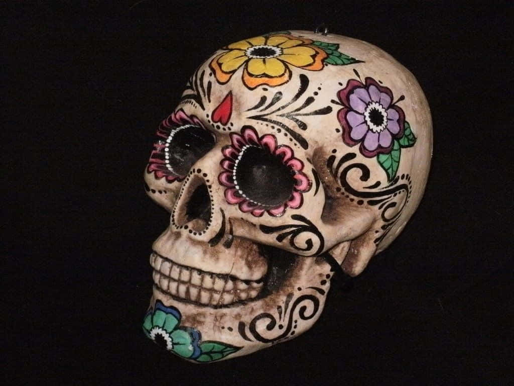 Day Of The Dead 桌布 壁紙 — 一個色彩鮮豔的糖骷髏，飾有彩色花朵和漩渦圖案，襯托在純黑背景上。