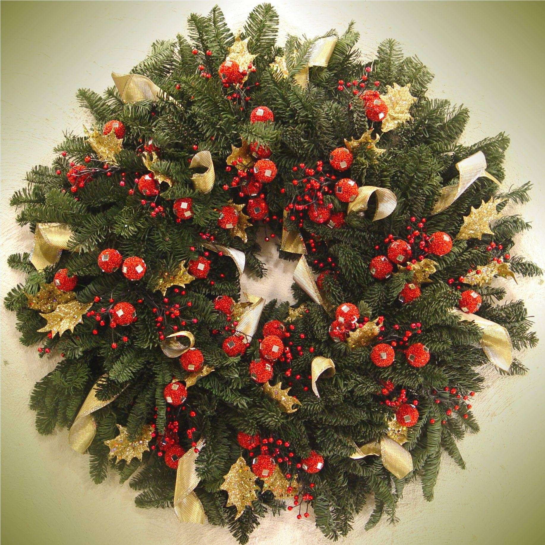 Wreath 桌布 壁紙 — 一個茂盛的綠色聖誕花環，飾有紅色漿果、閃閃發光的裝飾品和金色絲帶，背景是柔和的米色牆壁。
