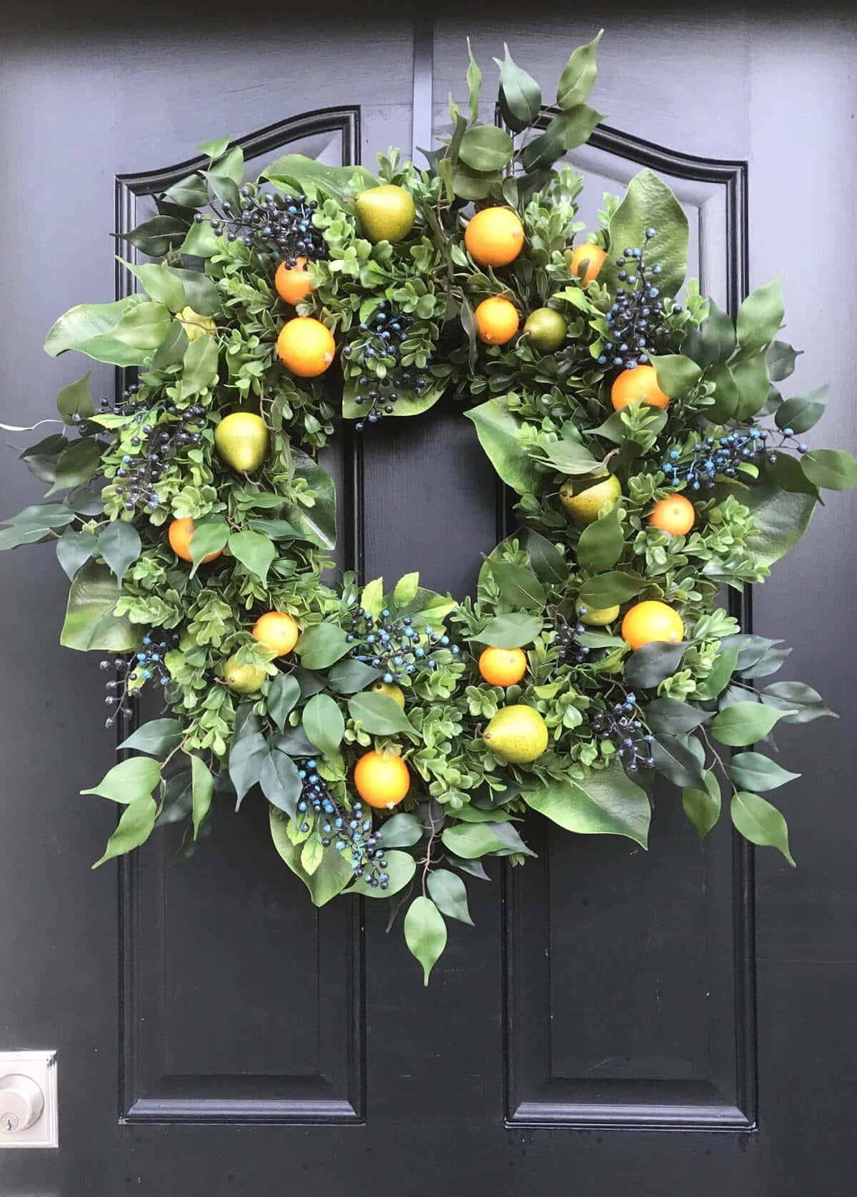 Spring Wreaths 桌布 壁紙 — 一個茂盛的綠色花環，飾有橙子和深色漿果，掛在時尚的黑色前門上。
