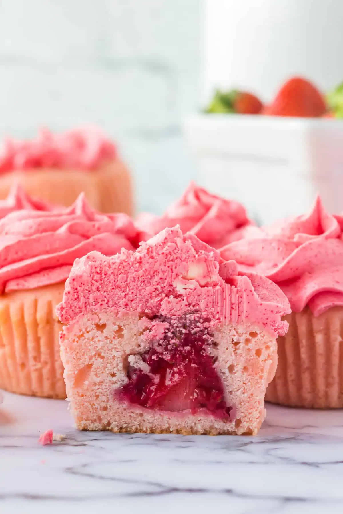 Pink Cupcakes 桌布 壁紙 — 一個草莓紙杯蛋糕的特寫，帶有粉紅色糖霜和中心暴露的多汁餡料。