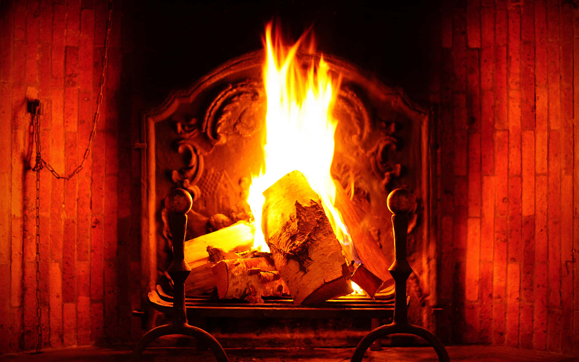 Autumn Fireplace 桌布 壁紙 — 一個華麗的壁爐中熊熊燃燒的火焰，將溫暖的橙色光芒投射在木牆和鐵製工具上。