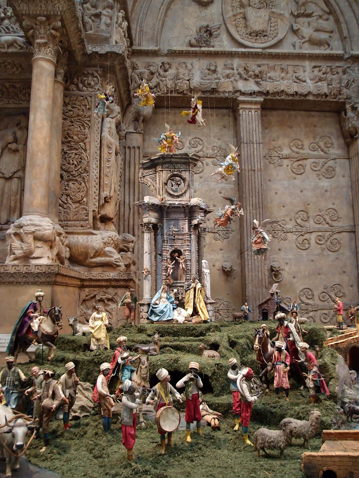 Nativity Scene 桌布 壁紙 — 一個華麗的宗教耶穌誕生場景，細節豐富的牧羊人、音樂家、動物和天使雕像，背景為雕刻石牆。