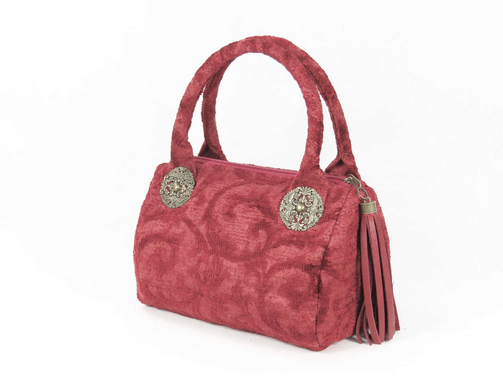 Red Handbag 桌布 壁紙 — 一個華麗的酒紅色天鵝絨手提包，飾有精緻的銀色獎章和相配的流蘇，背景為純白色。