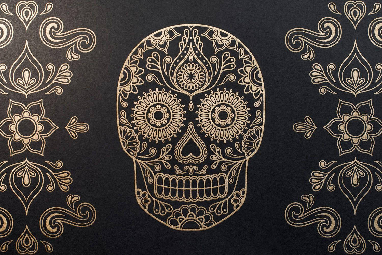 Dia De Los Muertos 桌布 壁紙 — 一個華麗的金色糖骷髏，帶有複雜的花卉圖案，位於深色紋理背景中央。
