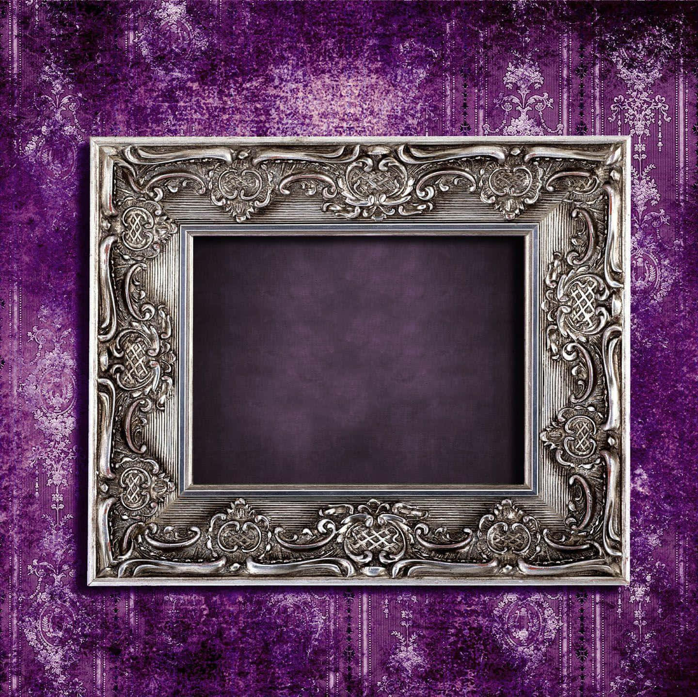 Frame 桌布 壁紙 — 一個華麗的銀色相框，帶有複雜的漩渦花紋，靠在帶有復古花卉圖案的紋理紫色壁紙上。