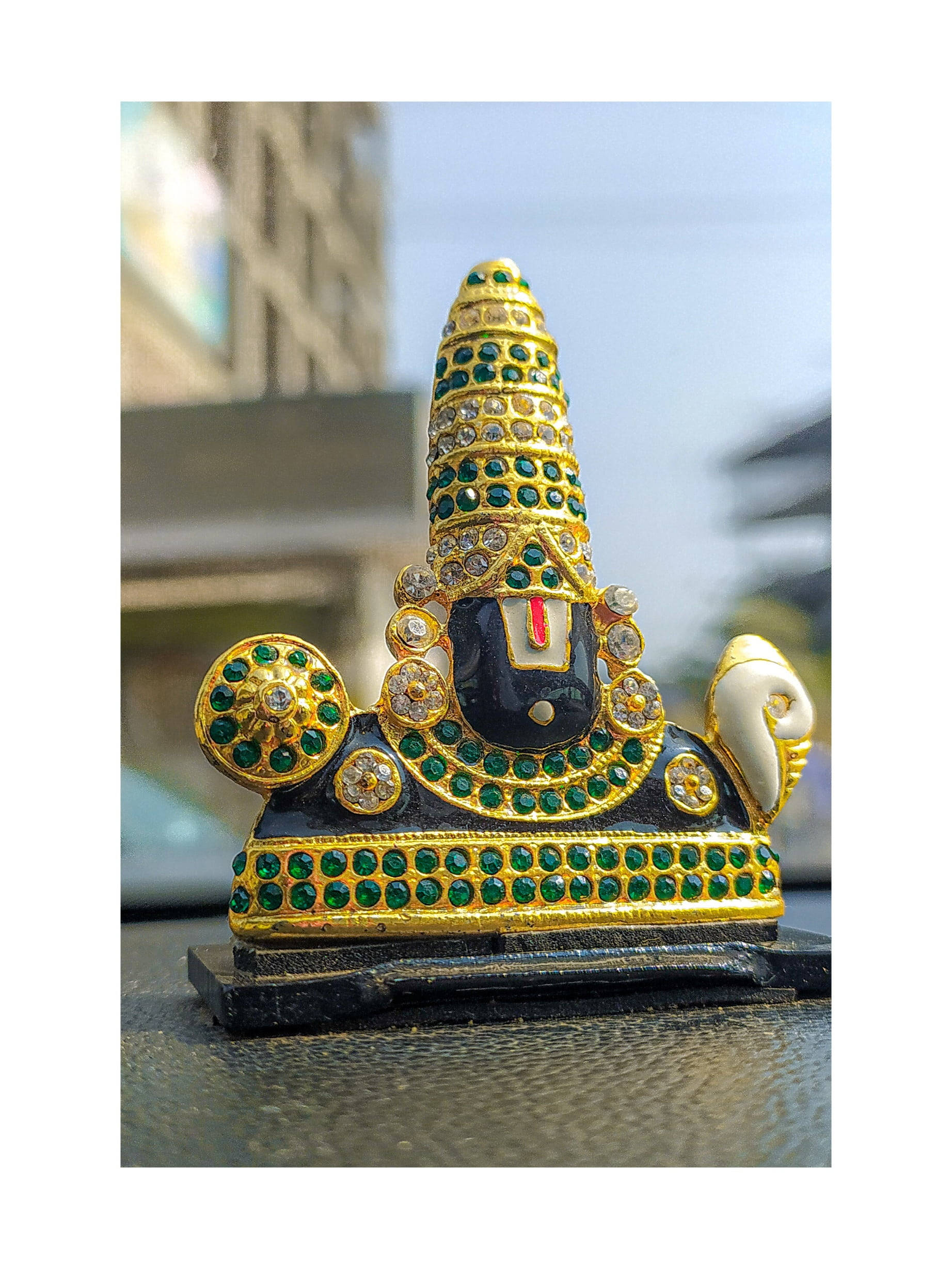 Vishnu 桌布 壁紙 — 一個華麗金色神像的特寫，飾有綠色和透明寶石，放置在紋理表面上。