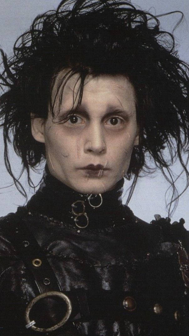 Edward Scissorhands 桌布 壁紙 — 一個蒼白哥德式人物的特寫肖像，擁有狂野的黑髮和深色化妝，穿著帶有金屬環的黑色皮革服裝。
