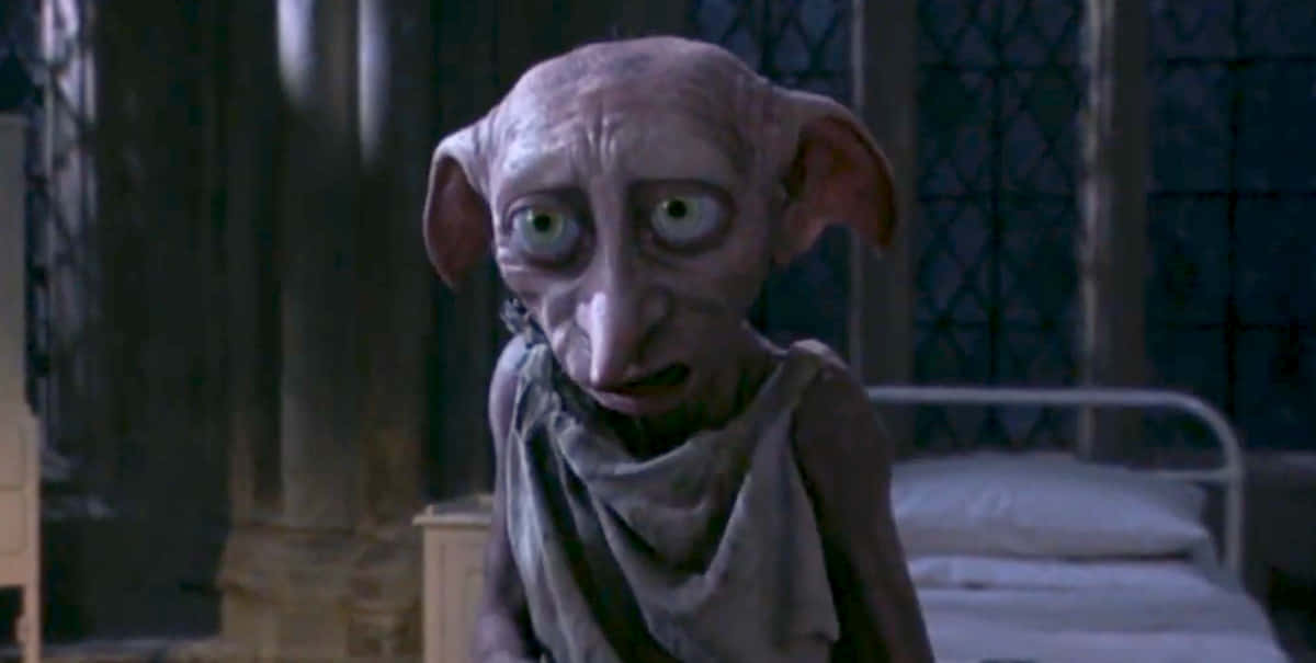 Harry Potter Dobby 桌布 壁紙 — 一個蒼白瘦削、大耳綠眼的生物在昏暗的石室中凝視著。