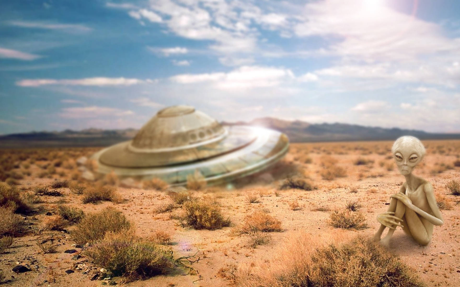 Alone 桌布 壁紙 — 一個蒼白的外星人坐在荒蕪的沙漠中，遠處有一隻飛碟在明亮的藍天下盤旋。