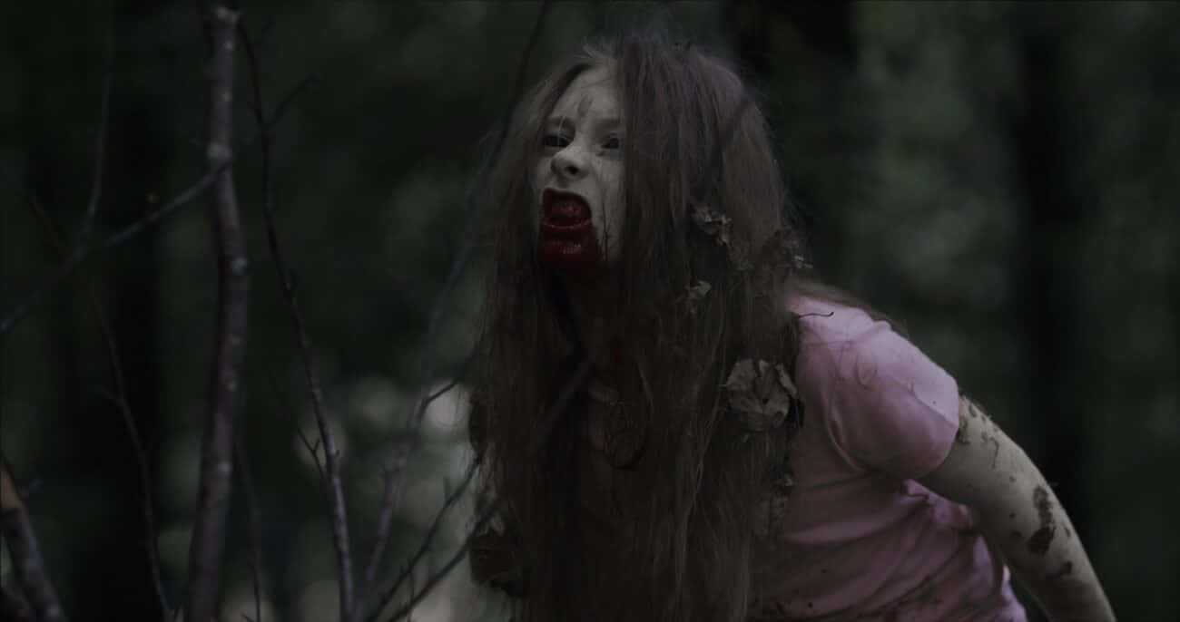 Scary Zombie 桌布 壁紙 — 一個蒼白的殭屍女孩，嘴巴沾滿鮮血，頭髮凌亂，在黑暗的森林中尖叫。