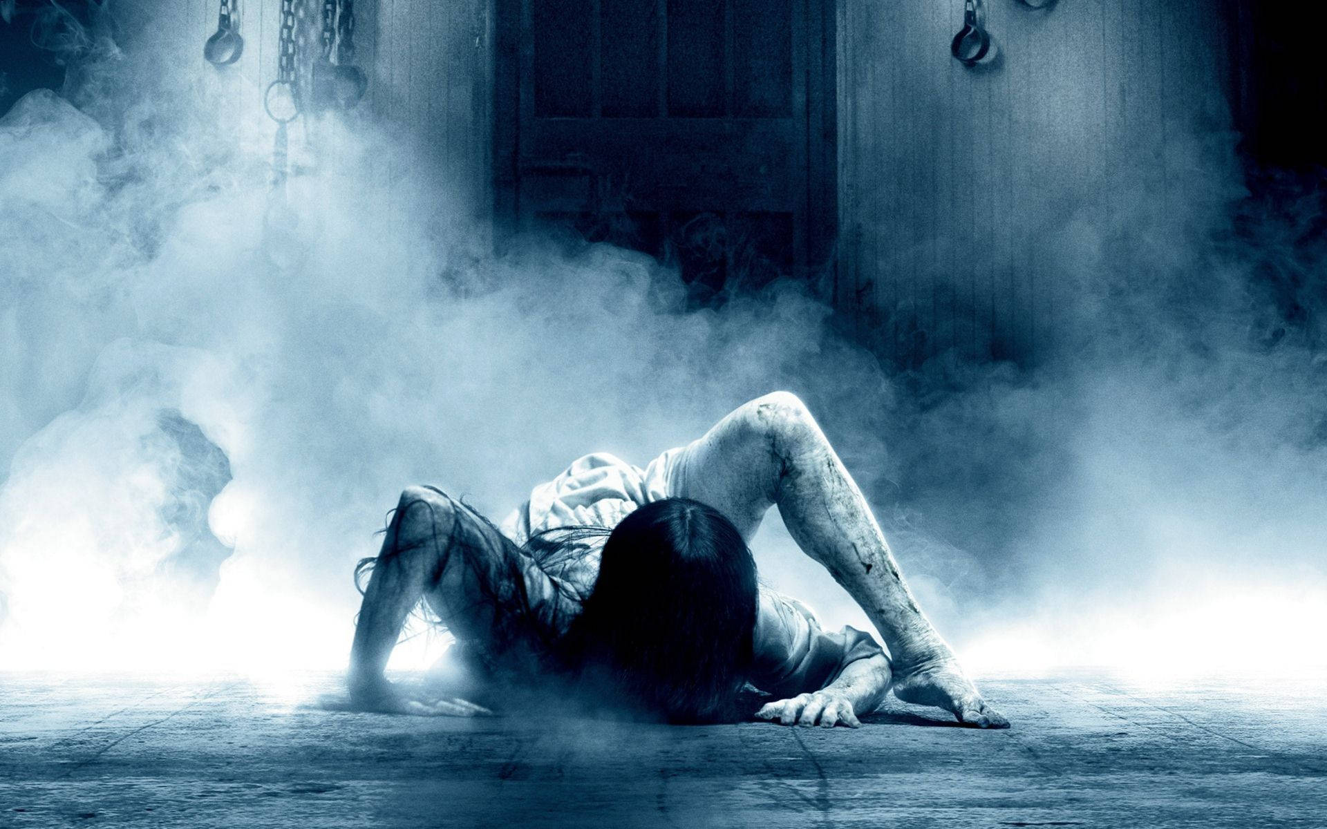 horror villains 桌布 壁紙 — 一個蒼白的身影在煙霧瀰漫、燈光昏暗、掛著鎖鏈和木門的詭異房間中爬行。