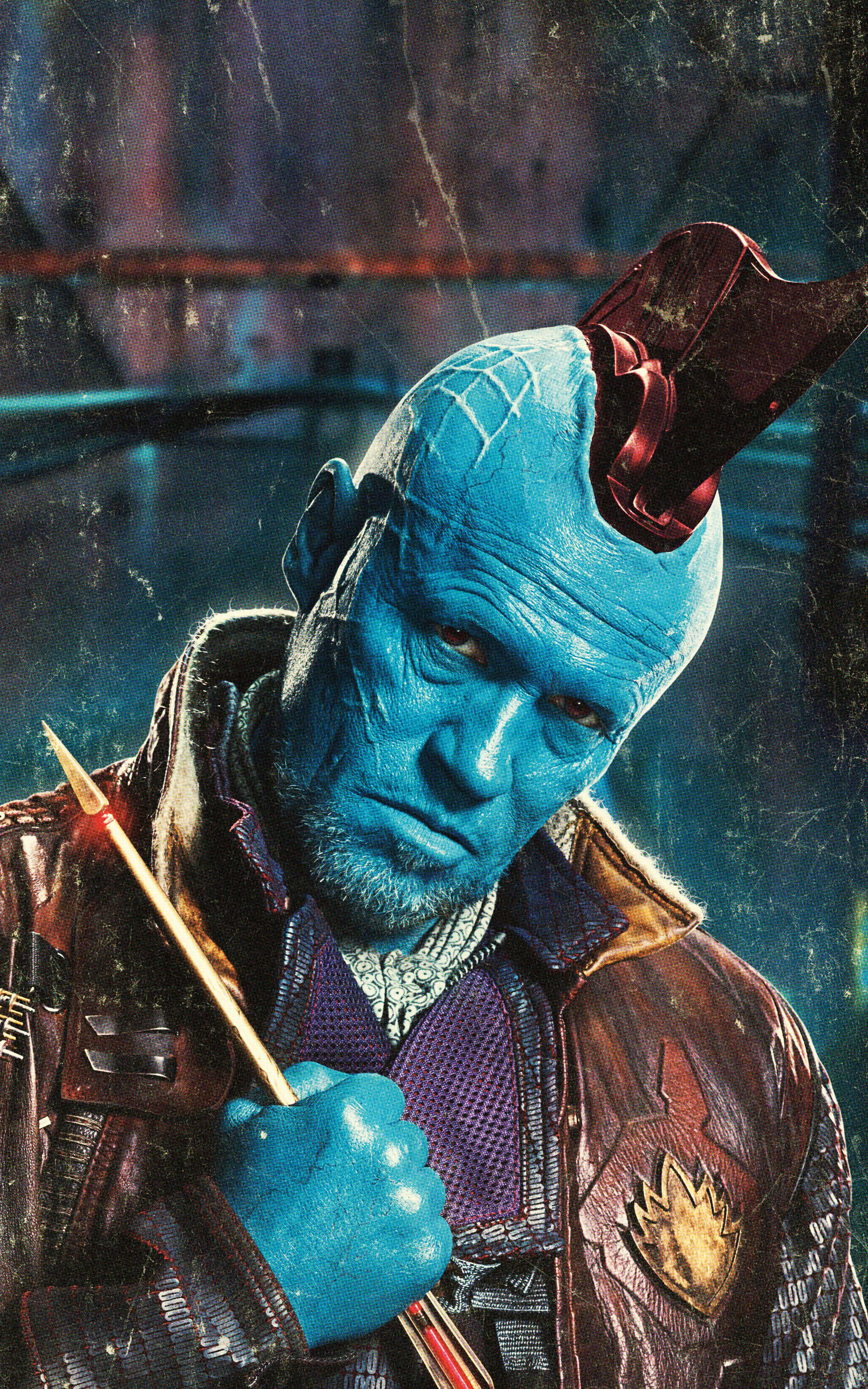 Yondu 桌布 壁紙 — 一個藍皮膚的外星人，留著紅色莫西乾頭，穿著皮夾克，在骯髒、有刮痕的環境中握著發光的武器。