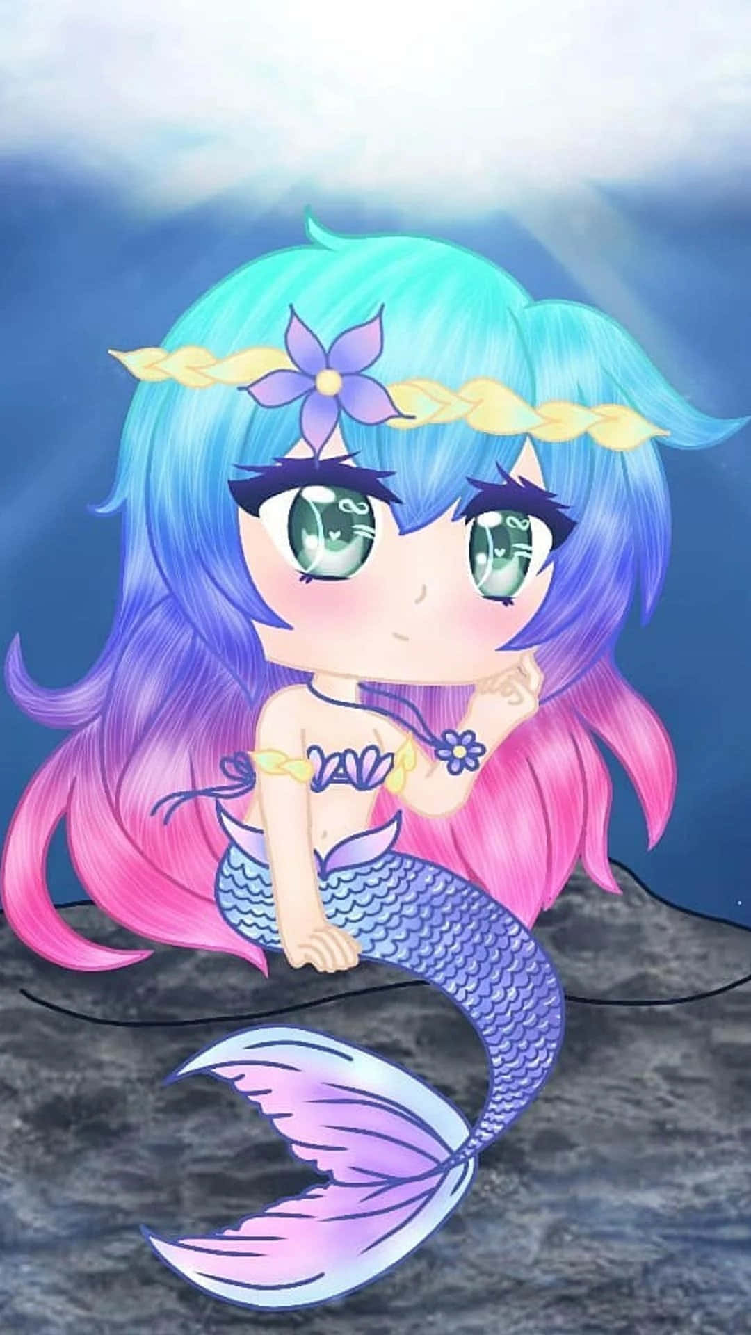 Gacha 桌布 壁紙 — 一個藍粉雙色頭髮、紫色尾巴的Q版美人魚坐在水底岩石上，用綠色大眼睛向上望。