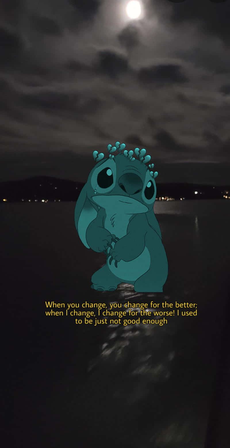 Sad Stitch 桌布 壁紙 — 一個藍綠色外星角色獨自站在黑暗的海岸線上，在明亮的月亮下帶著憂鬱的表情。