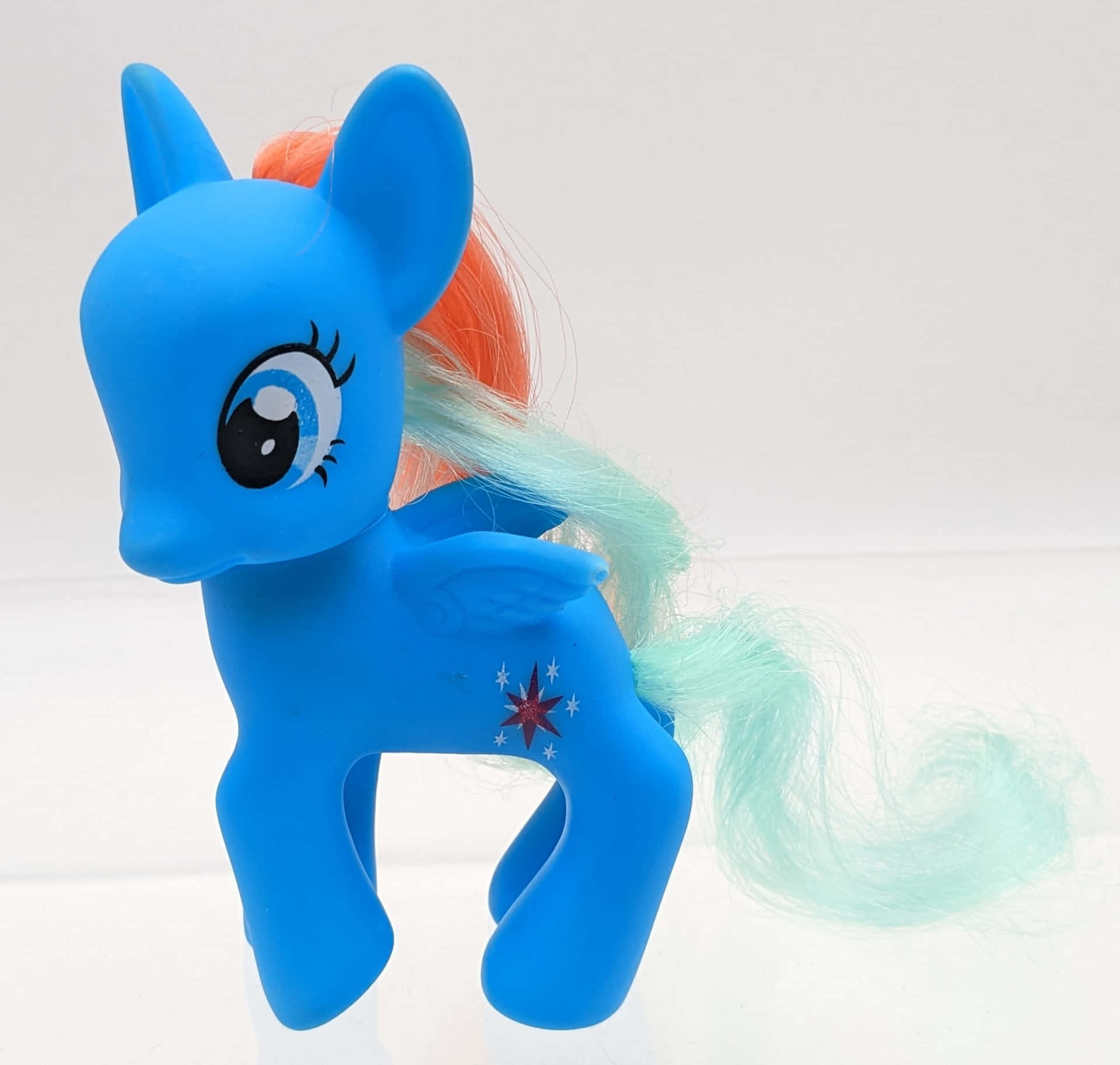 彩虹小馬 桌布 壁紙 — 一個藍色 My Little Pony 玩具，有橙色和藍綠色的鬃毛和尾巴，站在純白色背景前。