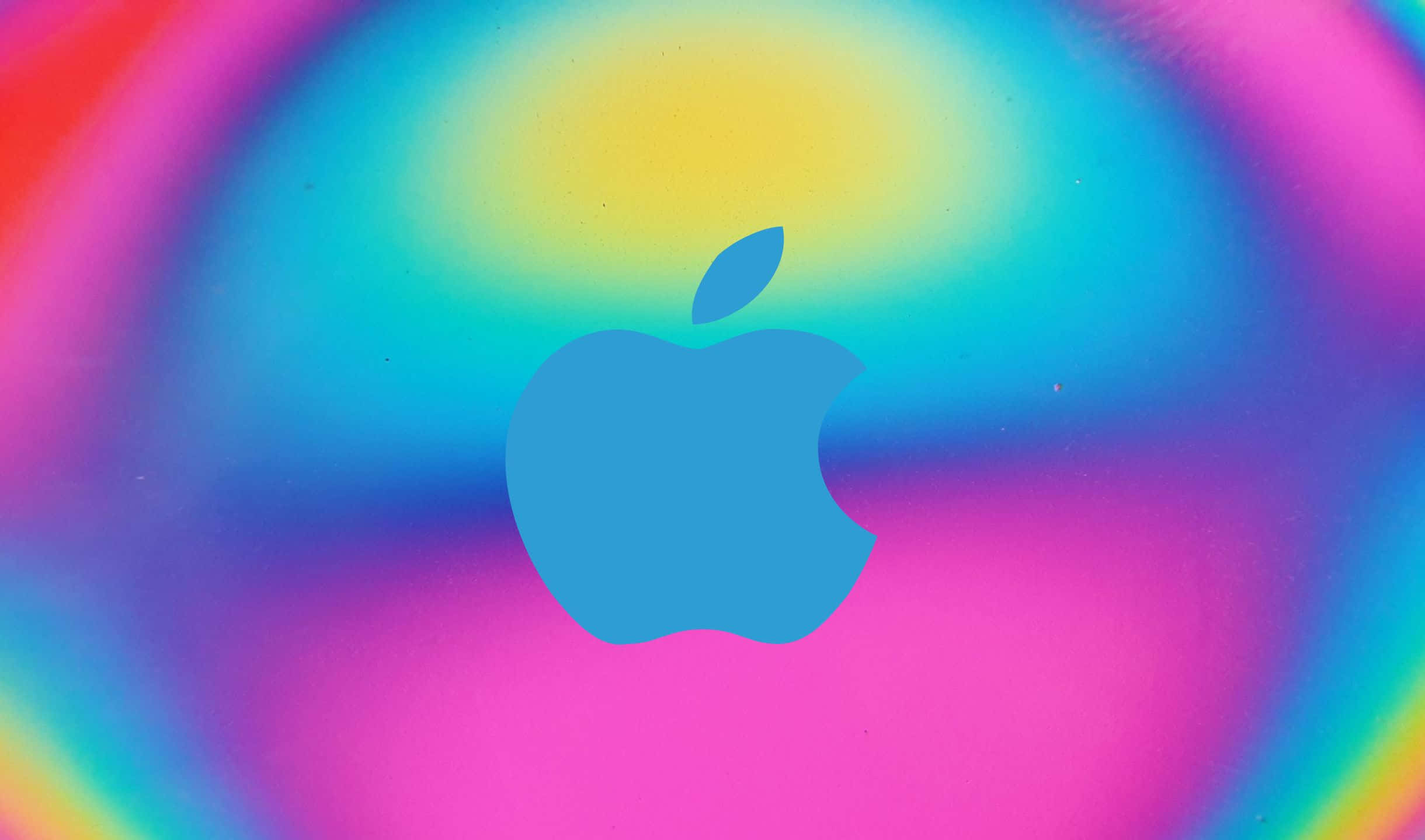 Blue Apple Logo 桌布 壁紙 — 一個藍色Apple標誌居中於充滿活力的彩虹漸變背景上，帶有柔和模糊的邊緣。