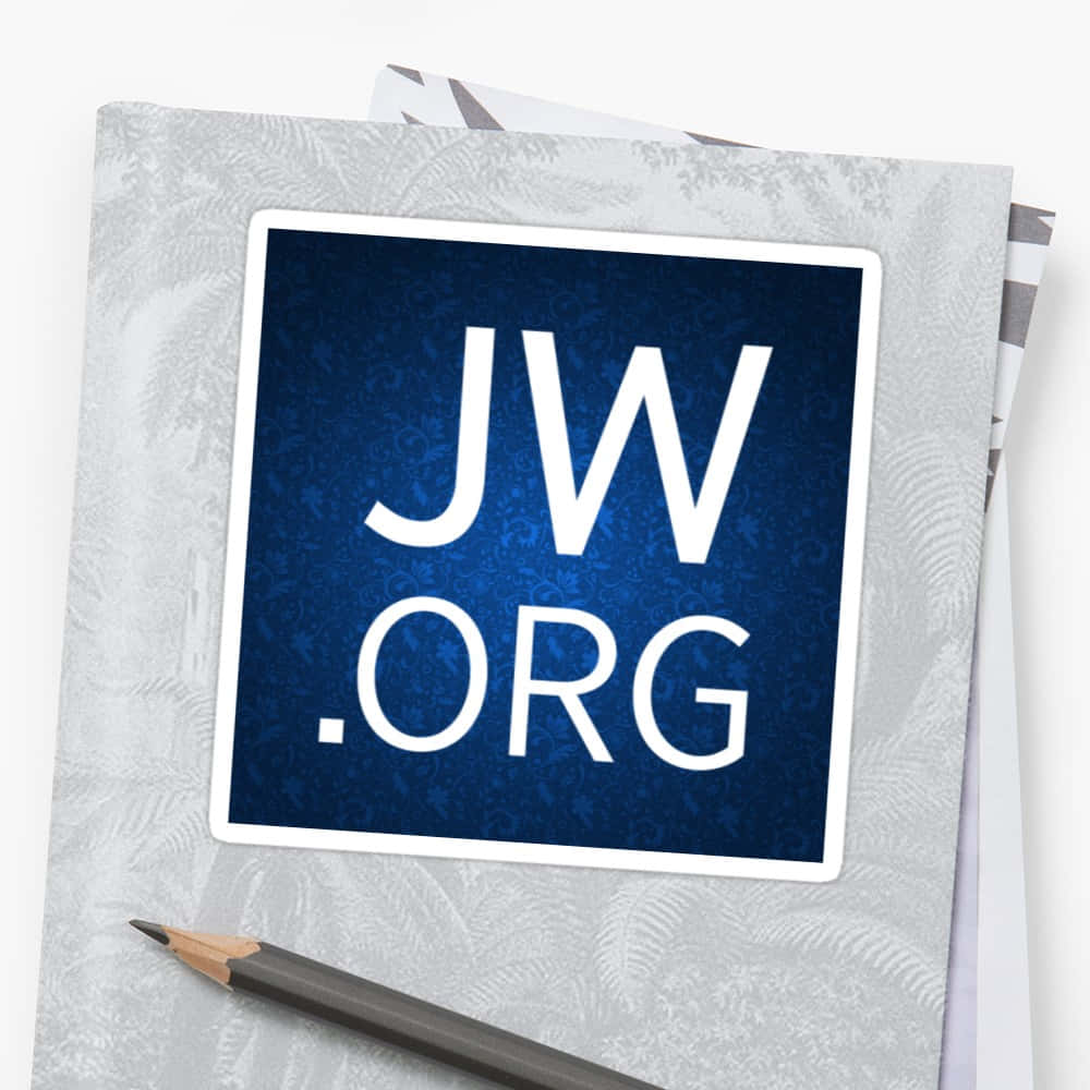 灰色 桌布 壁紙 — 一個藍色JW.ORG貼紙，上面有白色文字，放在一個有圖案的灰色筆記本上，旁邊有一支石墨鉛筆。
