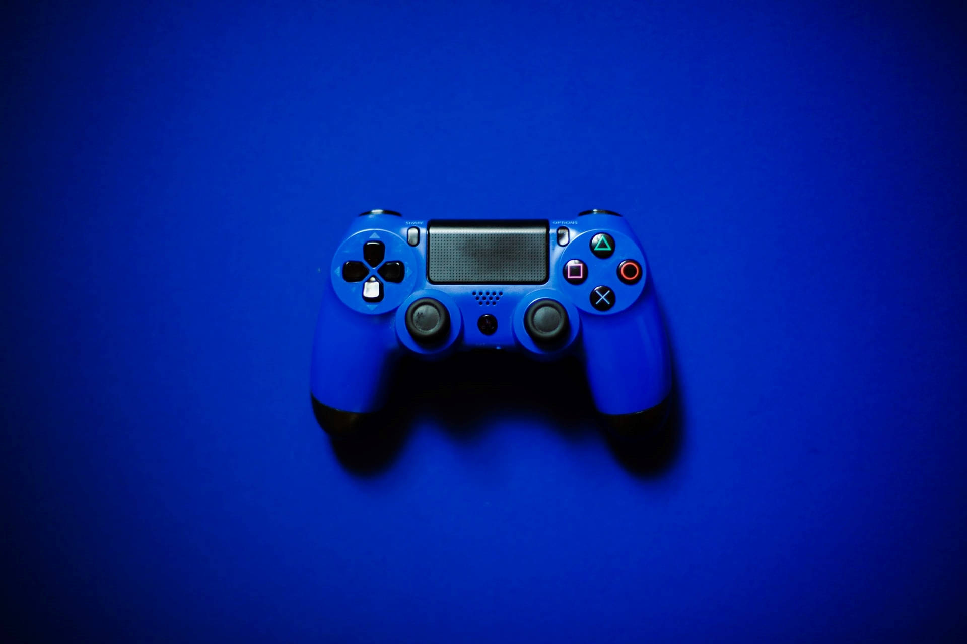 藍色美學 桌布 壁紙 — 一個藍色PlayStation手把放在純藍色背景中央，帶有柔和陰影。